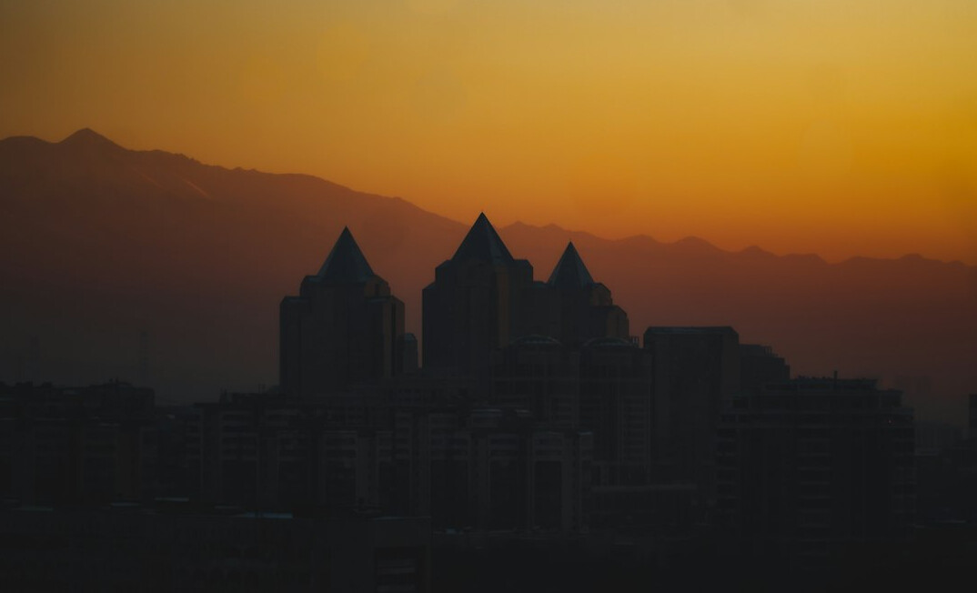 City skyline silhouette at dusk with mountains in the background